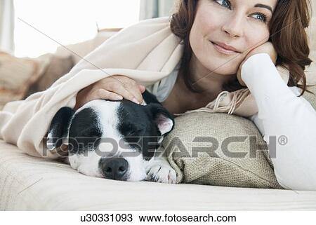 Woman relaxing on sofa with dog View Large Photo Image Stock Image - Woman relaxing on sofa with dog. Fotosearch