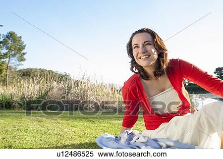 Stock Photography - Woman sitting in grass in park. Fotosearch