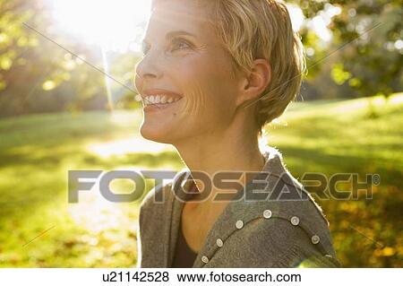 Woman smiling in park View Large Photo Image Stock Photo - Woman smiling in park. Fotosearch
