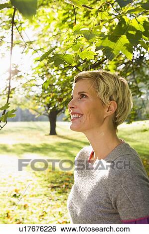 Woman smiling in park View Large Photo Image Stock Photograph - Woman smiling in park. Fotosearch