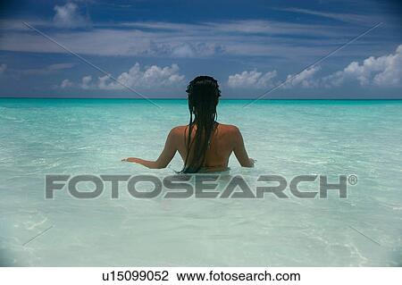 Stock Image - Woman standing in tropical water. Fotosearch