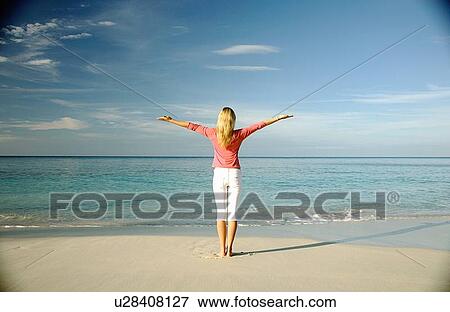 Stock Photo - Woman standing on tropical beach. Fotosearch