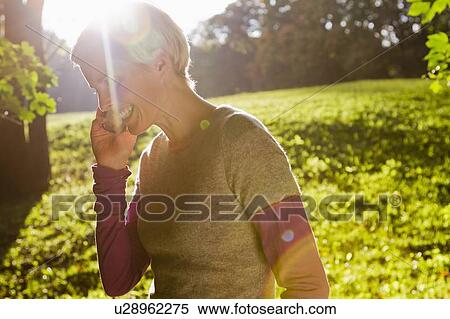 Stock Photography - Woman talking on cell phone in park. Fotosearch