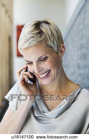Stock Image - Woman talking on cell phone outdoors. Fotosearch