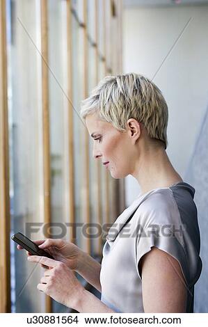 Picture - Woman using cell phone outdoors. Fotosearch