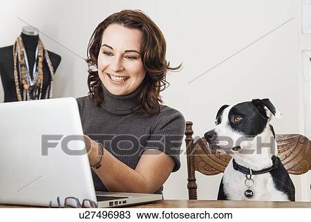 Woman using laptop with dog View Large Photo Image Stock Image - Woman using laptop with dog. Fotosearch