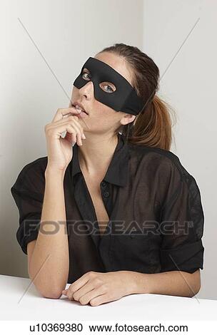 Stock Image - Woman wearing mask at desk. Fotosearch