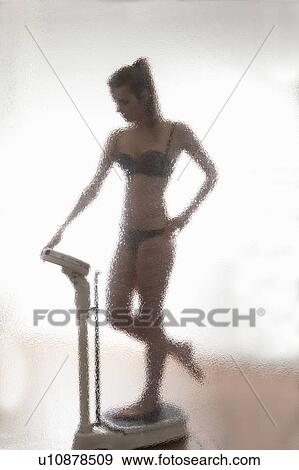 Stock Photo - Woman weighing herself in bathroom. Fotosearch