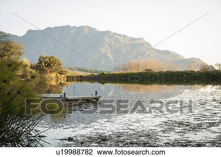 Wooden pier on still rural lake View Large Photo Image Stock Image - Wooden pier on still rural lake. Fotosearch