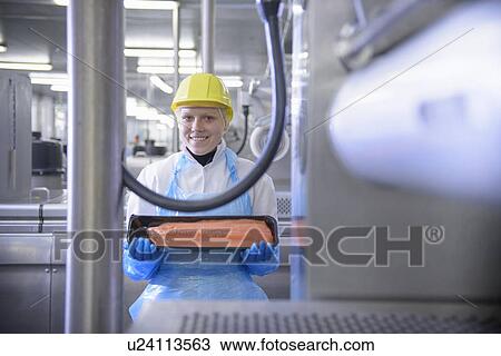 Stock Image - Worker holding fish filet in factory. Fotosearch