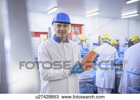 Stock Image - Worker holding fish filet in factory. Fotosearch