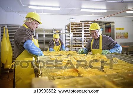 Stock Image - Workers examining smoked fish in factory. Fotosearch