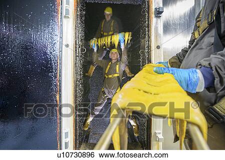 Stock Photograph - Workers smoking fish filets in factory. Fotosearch