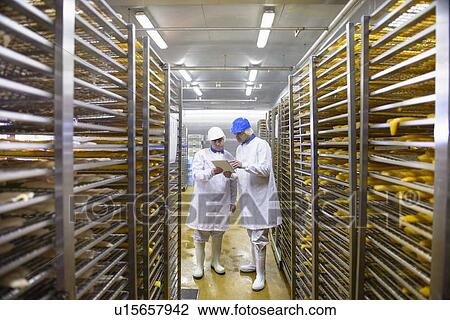 Stock Image - Workers talking in factory. Fotosearch