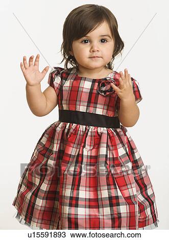 Stock Image - Baby girl ( 6-11 months) wearing plaid dress. Fotosearch