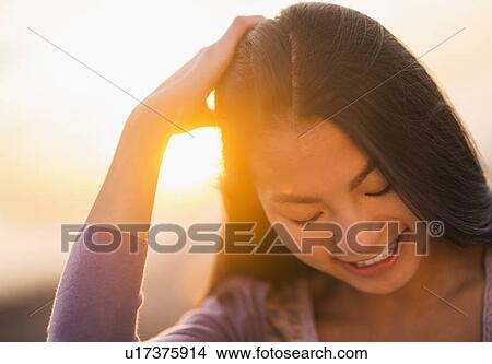 Picture - Close-up of smiling teenage girl ( 16-17 years) with sunset in background. Fotosearch