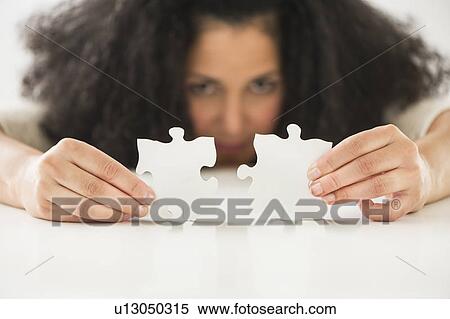 Stock Photography - Close up of woman's hands matching jigsaw puzzle. Fotosearch
