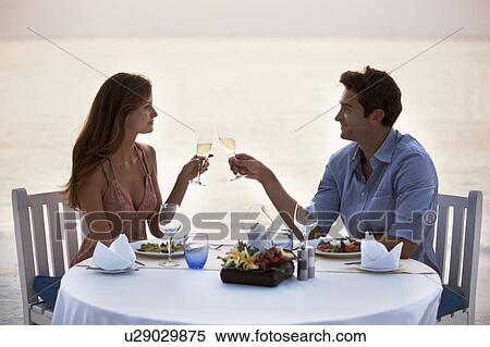 Stock Photography - Couple eating at table on tropical beach. Fotosearch