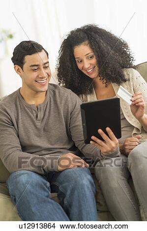 Picture - Couple using digital tablet on sofa. Fotosearch