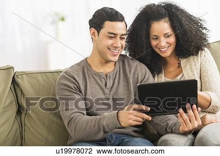 Couple using digital tablet on sofa View Large Photo Image Stock Image - Couple using digital tablet on sofa. Fotosearch