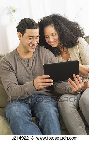 Couple using digital tablet on sofa View Large Photo Image Stock Photo - Couple using digital tablet on sofa. Fotosearch