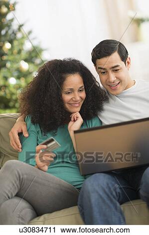 Stock Image - Couple using laptop for online shopping. Fotosearch