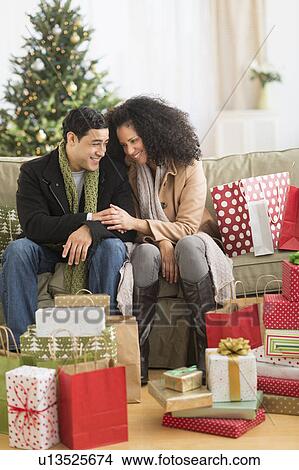 Couple with Christmas presents in living room View Large Photo Image Picture - Couple with Christmas presents in living room. Fotosearch