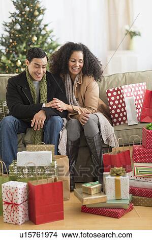 Couple with Christmas presents in living room View Large Photo Image Picture - Couple with Christmas presents in living room. Fotosearch