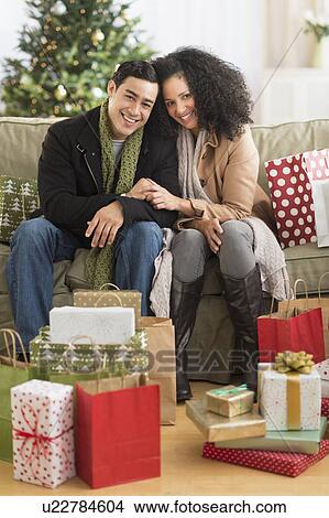 Couple with Christmas presents in living room View Large Photo Image Picture - Couple with Christmas presents in living room. Fotosearch