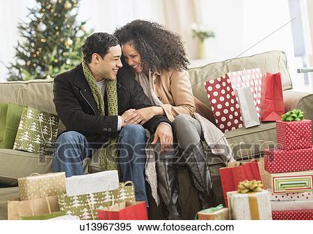 Stock Photography - Couple with Christmas presents in living room. Fotosearch