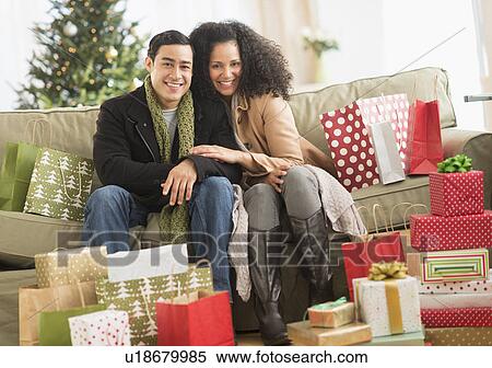 Stock Photography - Couple with Christmas presents in living room. Fotosearch
