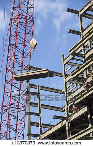 Stock Photo - Crane lifting parts of metal frame. Fotosearch