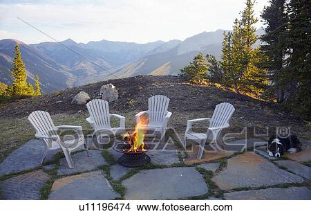 Dog lying down by fire pit and four empty chairs View Large Photo Image Picture - Dog lying down by fire pit and four empty chairs. Fotosearch