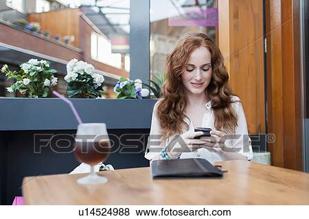 Stock Photo - Elegant woman in cafe using mobile phone. Fotosearch