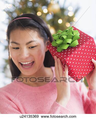 Stock Photo - Front view of teenage girl ( 16-17 years) holding Christmas gift. Fotosearch