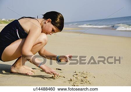 Stock Image - Girl (8-9) playing at beach. Fotosearch
