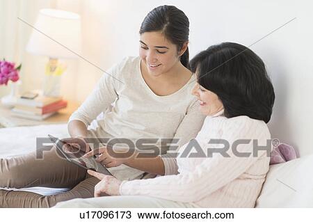 Grandmother and granddaughter (16-17) lying on bed with digital tablet View Large Photo Image Stock Image - Grandmother and granddaughter (16-17) lying on bed with digital tablet. Fotosearch