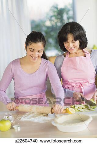 Stock Image - Grandmother and granddaughter (16-17) baking together. Fotosearch