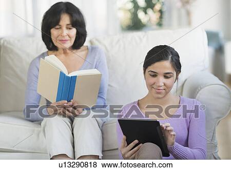 Grandmother reading book and granddaughter (16-17) sitting with digital tablet View Large Photo Image Stock Photo - Grandmother reading book and granddaughter (16-17) sitting with digital tablet. Fotosearch