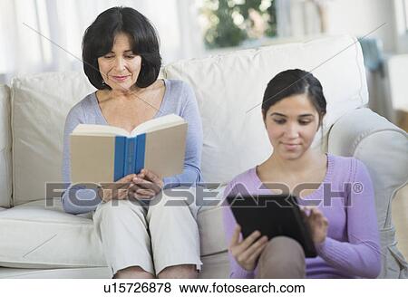 Grandmother reading book and granddaughter (16-17) sitting with digital tablet View Large Photo Image Stock Photo - Grandmother reading book and granddaughter (16-17) sitting with digital tablet. Fotosearch