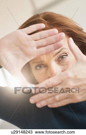 Stock Image - Hands framing face of businesswoman. Fotosearch