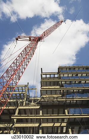 Stock Image - Low angle view of crane and building under construction. Fotosearch