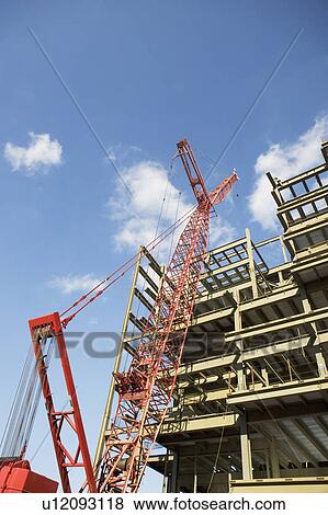 Low angle view of crane and building under construction View Large Photo Image Stock Photo - Low angle view of crane and building under construction. Fotosearch