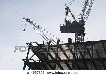 Stock Photograph - Low angle view of crane and building under construction. Fotosearch