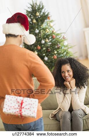 Picture - Man holding Christmas gift for woman. Fotosearch