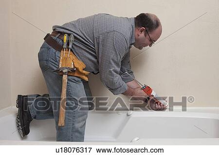 Man with Caulk Gun working in bathroom View Large Photo Image Stock Photo - Man with Caulk Gun working in bathroom. Fotosearch