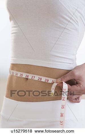 Midsection of woman measuring waistline View Large Photo Image Stock Photo - Midsection of woman measuring waistline. Fotosearch