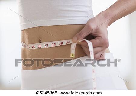Midsection of woman measuring waistline View Large Photo Image Stock Photography - Midsection of woman measuring waistline. Fotosearch