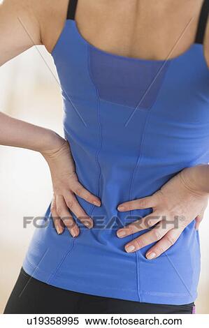 Stock Photography - Midsection of woman with hands on back. Fotosearch