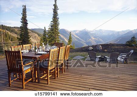 Stock Image - Outdoor table and chairs on wooden terrace. Fotosearch